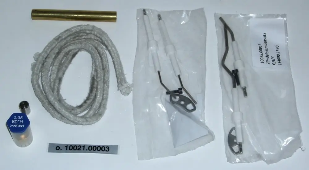 Daikin Service-Kit mit einem Kunststoffrohr, einer Schnur, mehreren Zündelektroden in Verpackungen sowie einem Danfoss-Bauteil.